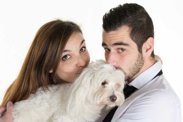 Feliz pareja besando a su perro blanco en el sofá en casa — Foto de Stock