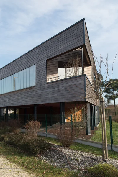Edificio moderno con un lado con paneles de madera bajo el cielo azul — Foto de Stock