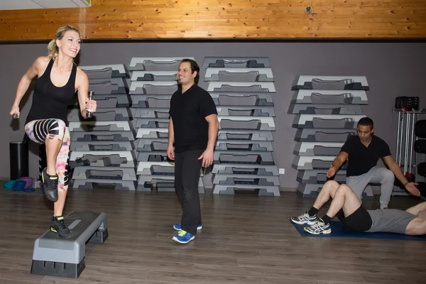 Egzersiz ve spor salonunda adım platformlarda bacaklar esneme gülümseyen insanların grup — Stok fotoğraf