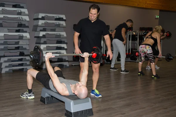 Adam ve eğitmen, halter ağırlıkları ile spor salonunda egzersiz — Stok fotoğraf