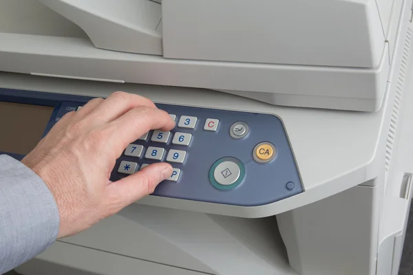 Homem segurando o dedo no botão Iniciar da impressora a laser — Fotografia de Stock