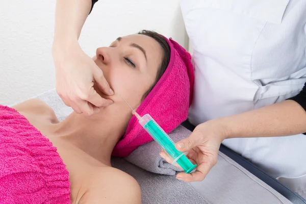 Attractive woman at plastic surgery with syringe in her face — Stock Photo, Image