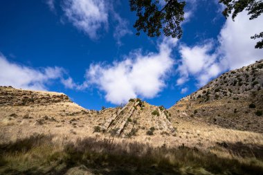 Büyük dağın altından mavi gökyüzüne bakıyorum.