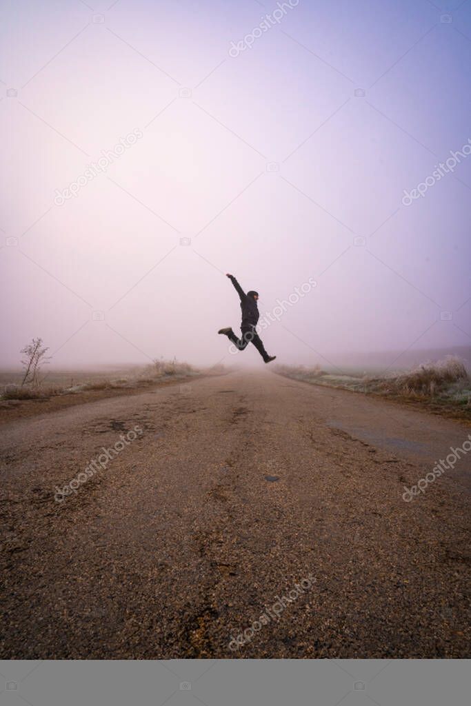 man jumping on the road on a foggy day