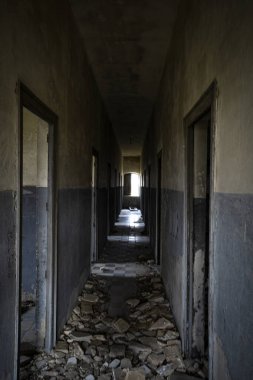 Yerdeki molozlarla harabelerde terk edilmiş büyük bir evin iç koridoru.