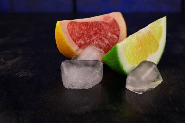 Koyu ahşap arka planda buzlu sulu limon ve greyfurt dilimleri.