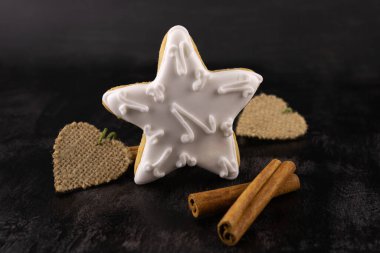 Zencefilli çörek, tarçın çubukları ve siyah ahşap arka planda yakın plan yün kalpler