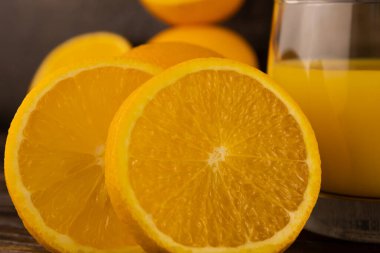 Dilimlenmiş portakallar ve koyu bir arka planda bardakta meyve suyu.