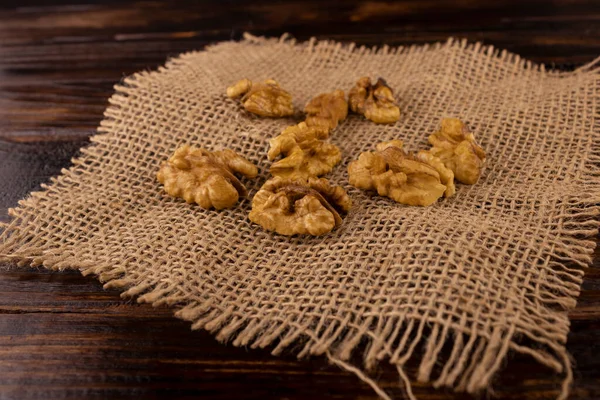 a scattering of walnut seeds on burlap on a wooden background close-up