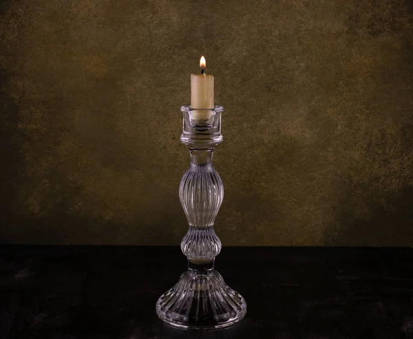 crystal candle holder with a burning candle on a camouflage background