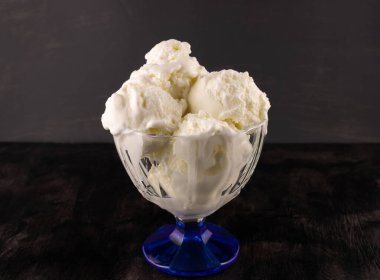 Koyu ahşap arka planda vazoda erimiş dondurma topları.