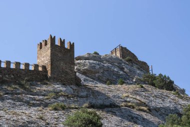 Bir kayanın üzerindeki antik bir kule, bir kalenin kalıntıları, taştan yapılmış binalar.