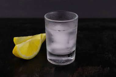 Koyu ahşap arka planda iki dilim limonlu buzlu votka..