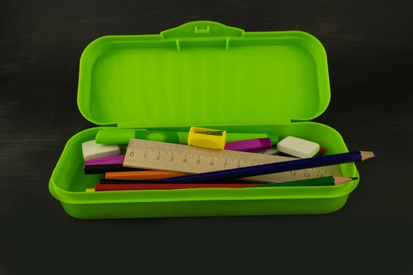 在黑暗的背景下 一个绿色铅笔盒 里面有学校用品 — 图库照片