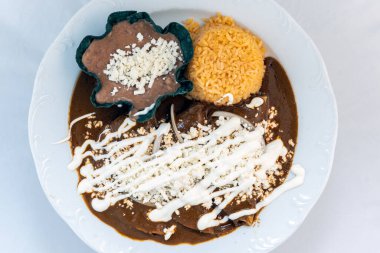 Pirinç ve kızarmış fasulye ile servis edilen enchiladas köstebeğinin genel manzarası çok çekici görünüyor..