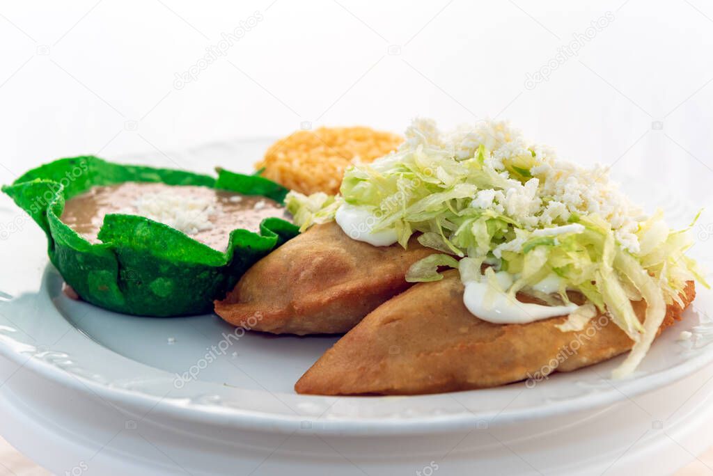 Quesadillas fritas servidas con arroz y tazón de tortilla frijoles refritos se ve y sabe