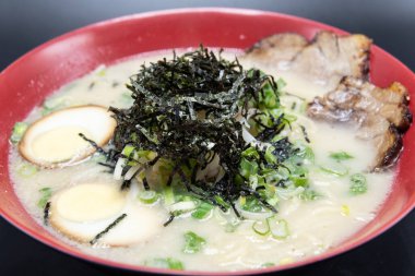 Büyük bir kase baharatlı Tonkotsu Ramen. Üstünde bir yığın yosun ve haşlanmış domuz eti ile haşlanmış yumurta var..