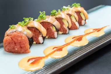 Firery taste satisfied with these pieces of sushi stuffed with spicy tuna and shrimp and topped with salmon with a decorate presentation on the plate.