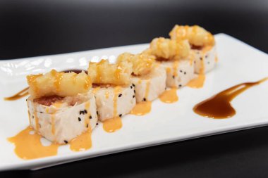 Sushi pieces wrapped in soy paper filled with crab meat and topped with fried shrimp.