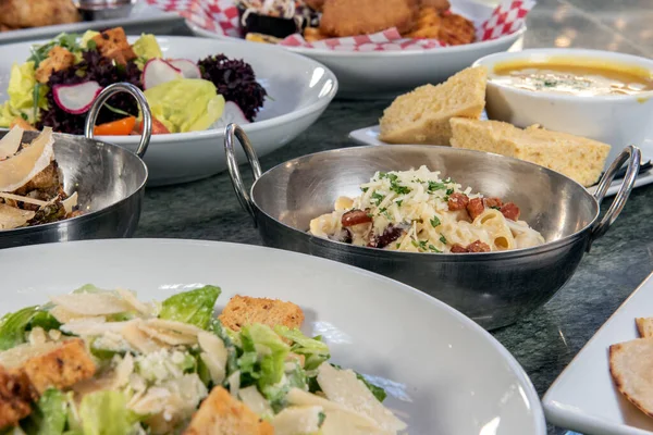 Ortasında makarna ve peynir kasesi olan bir sürü restoran yemeği var..