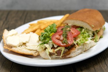 Büyük Churrasquito sandviçi üzerine patates kızartması ile servis edilen sulu domates dilimleri ile açılır..