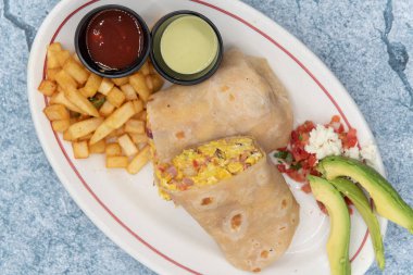 Kahvaltı burrito 'sunun genel görünüşü yumurta ve et yığınlarını ortaya çıkarmak için ikiye bölünmüştür..