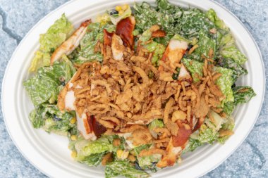 Barbekü tavuk salatasının yukarıdan görünüşü romaine, tavuk göğsü, marul ve iştahı doyurmak için sosla dolu..