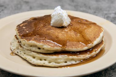 Akçaağaç şurubu damlayan ve üzeri çırpılmış tereyağlı krep yığını..