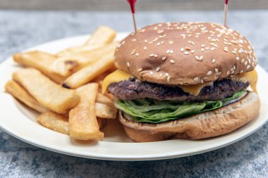 Eritilmiş peynirli ve dolgulu çizburger ile kalın bir biftek kızartması karışımı..