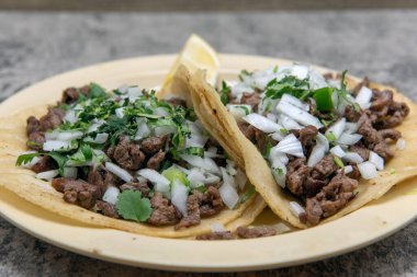 Çift katmanlı sıcak mısır tortillası içinde doğranmış biftek ve soğanla dolu bir çift carne asada taco..