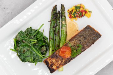 Kuşkonmaz ve ıspanakla servis edilen ızgara somon bifteğinin deniz ürünleri iştahını gidermek için genel manzarası..