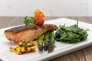 Kuşkonmaz ve ıspanakla servis edilen ızgara somon bifteği deniz ürünlerinin iştahını açar..