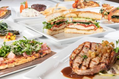 Önünde leziz bir domuz pirzolası olan farklı restoran tabakları..