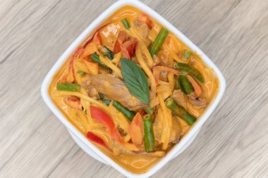 Ahşap bir masa üzerinde servis edilen tabakta sunulan baharatlı kırmızı köri manzarası..