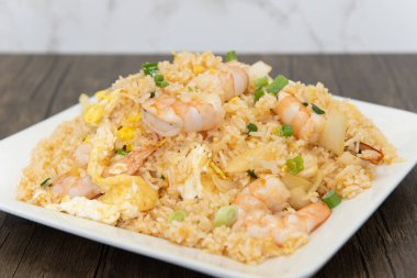 Karides ve sebzeli büyük bir pilav yığını. Baharatlı aşermeyi tamamlamak için bir tabak..