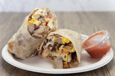 Kahvaltılık burrito, yanında salsa ile servis edilen tortillayı dolduran malzemeleri göstermek için ikiye bölündü..