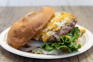 Kocaman bir cheeseburger ve yanında patates kızartması..