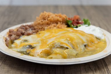 Bu yeşil enchilada 'lar öğle yemeğinde Meksika pilavı ve fasulyesi ile servis ediliyor..