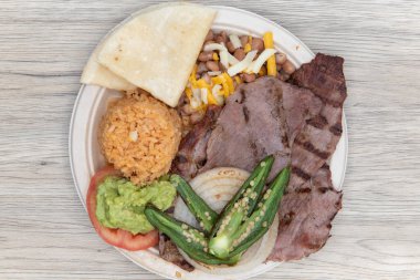 Izgara carne asada bifteği, sıcak pilav ve biber ile servis edilir..