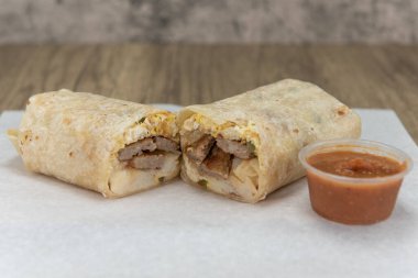 Sosisli kahvaltılık burrito, baharatlı sosla birlikte sosu da göstermek için ikiye bölündü..