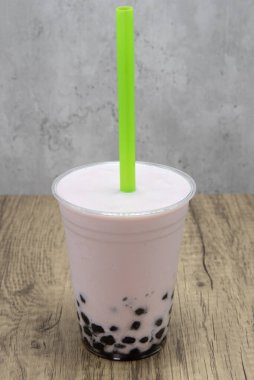 Tatlandırmak için bardağın altında tapyoka boba topları bulunan çilek aromalı smoothie..