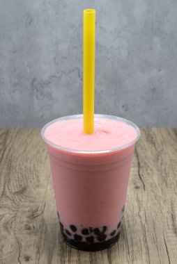 Tatlandırmak için bardağın altında tapyoka boba topları bulunan Stawberry aromalı smoothie..