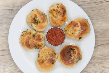 Marinara sosuyla servis edilen bir tabakta sarımsak aromalı ekmek rulolarının mezeleri..