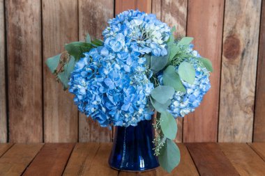 Mavi vazodaki düzenlenmiş mavi Hydrongea çiçeklerinden oluşan güzel bir buket..
