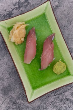 Asya yemeği için aperatif olarak bir çift sarı kuyruklu nigiri ile suşi tabağı..