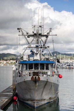Görevde olmayan tekneler limanın rıhtımlarına demirlemiş bulutlu hava altında..