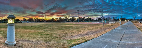 Wandelpad langs softbal veld verlicht door gloeiende lichten. — Stockfoto