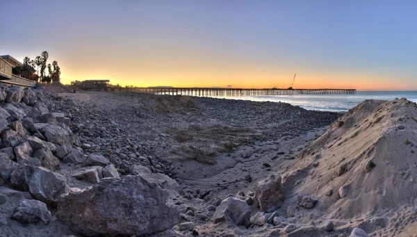 Pier between the mounds of sand and rocks — Stock Photo, Image