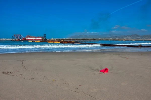Красное ведро, вырытое в песке . — стоковое фото