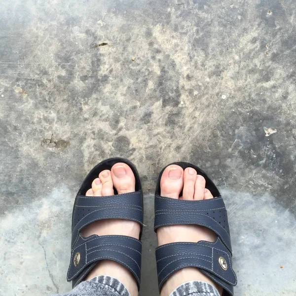 Scarpe astratte piedi in piedi su vecchio calcestruzzo. Infradito Hipster — Foto Stock